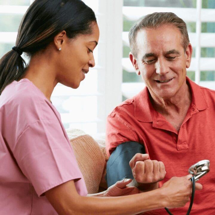 A woman is checking the blood pressure of an older man.