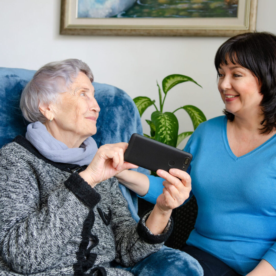 A woman showing an older lady something on her phone.